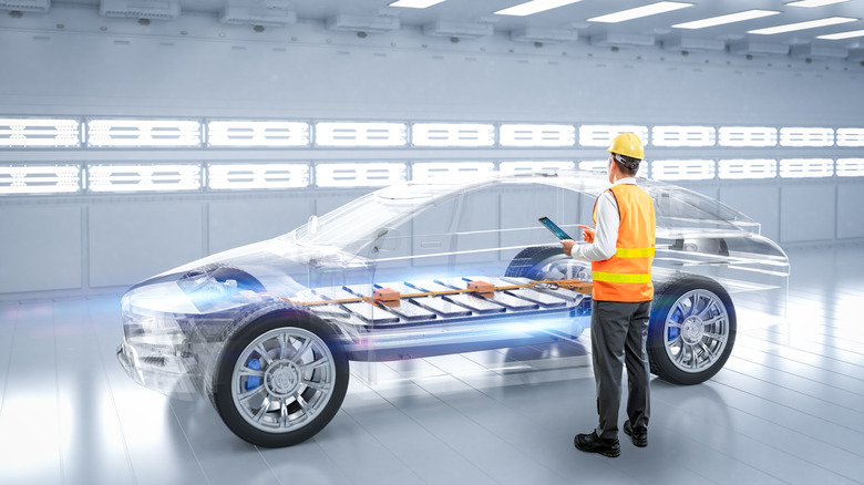 A CG representation of an EV with internal components visible as an engineer in a high-visibility vest and hard hat looks on and makes notes on a tablet.