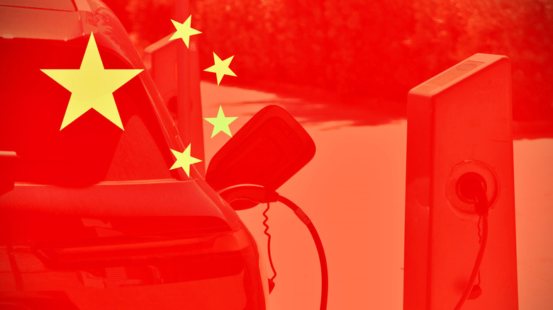 Chinese flag with a charging electric car seen in the background through transparency.