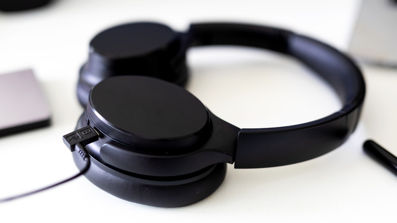 A pair of wireless headphones with a charging cable plugged in.