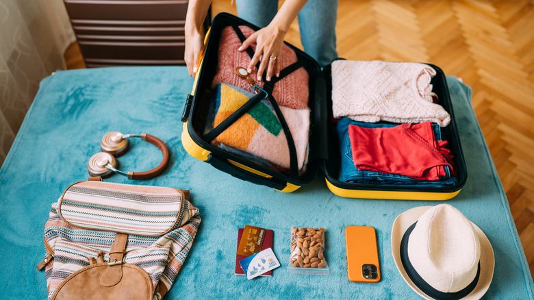 A person packing a travel suitcase.