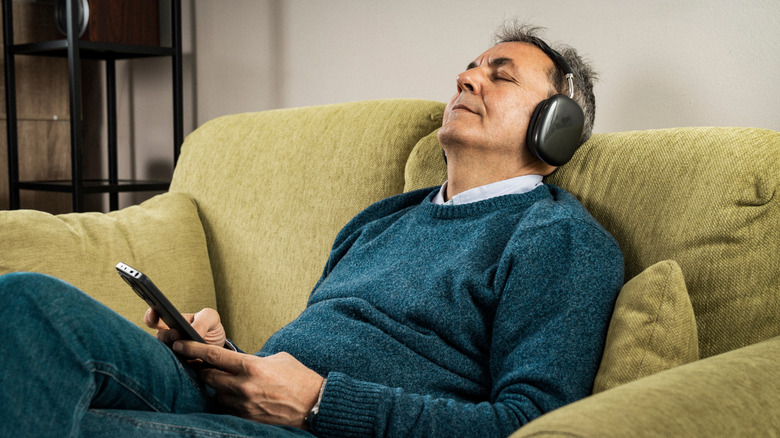 A man on a sofa wearing wireless headphones.