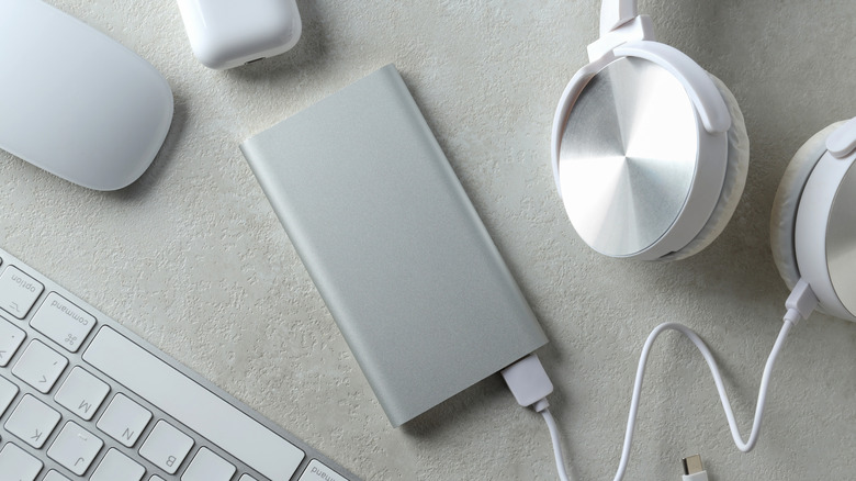 A pair of wireless headphones plugged into a power bank.