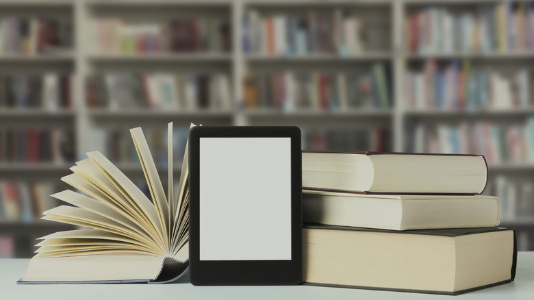 Kindle placed alongside hardcover books on a table in a library
