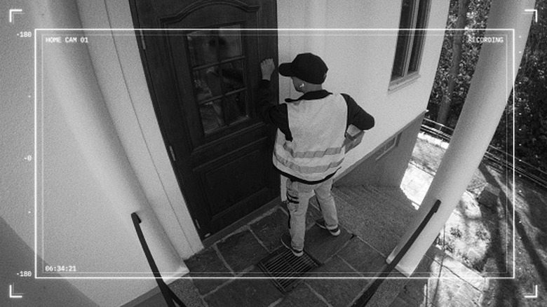 View of a security camera feed with a package courier knocking on the door to a home