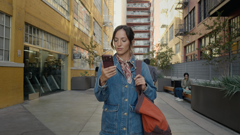 A woman holds an iPhone 18 Pro on the street