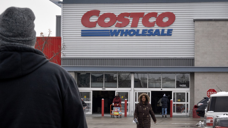 People walking in and out of a Costco storefront.