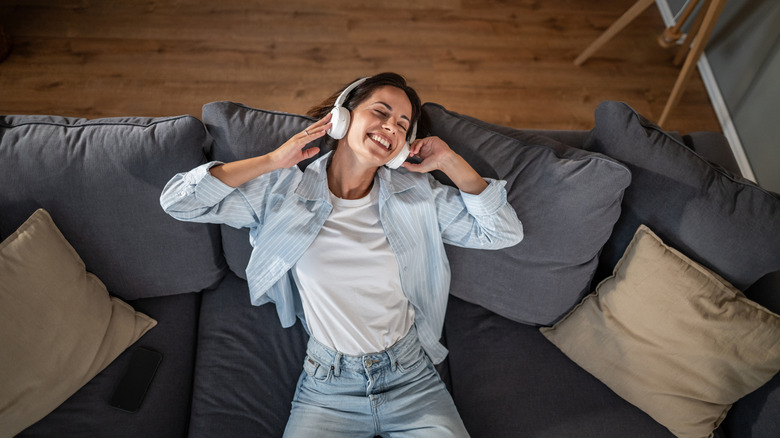 A woman listens to wireless headphones on the couch