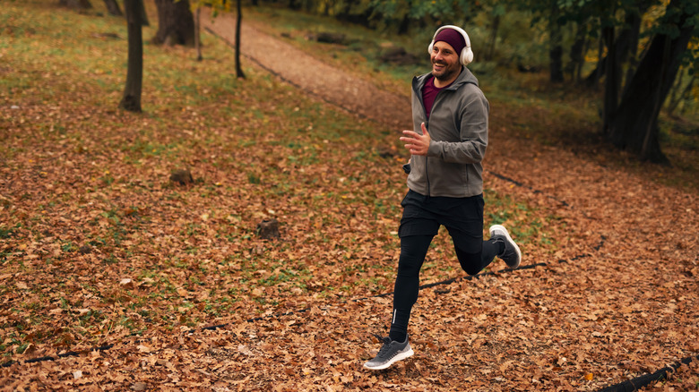 A man runs through the park wearing wireless headphones