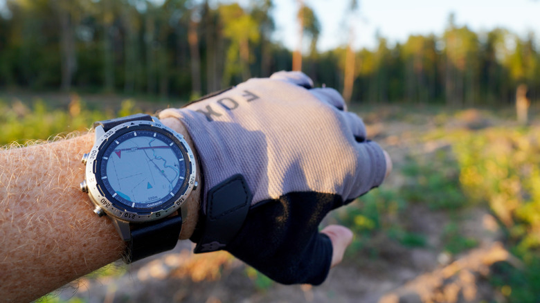 A Garmin watch with a map on the display and dirt trail in the background