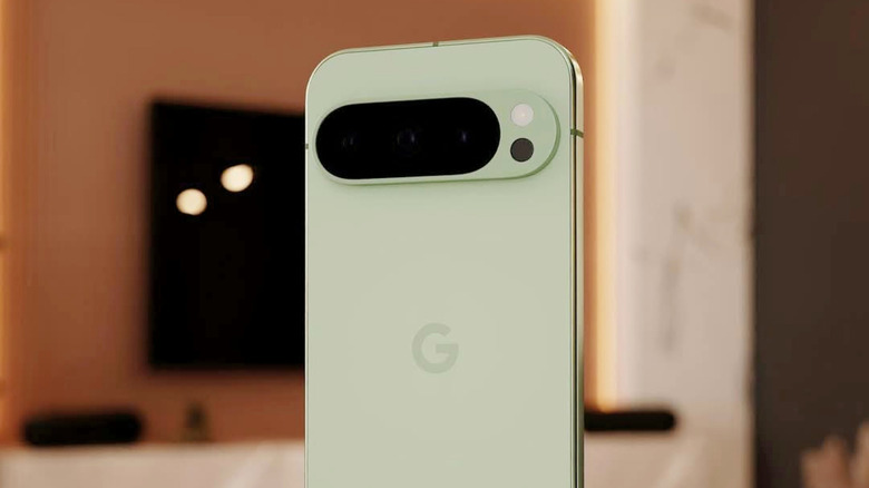 Pixel 10 Pro in green standing up with TV on wall behind it, showing rear of phone