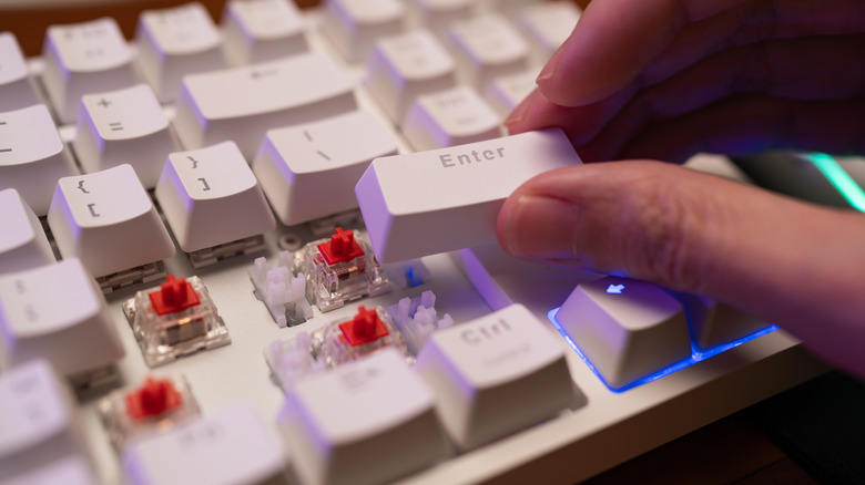 A hand removing keys from a mechanical keyboard