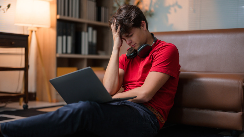 Frustrated college student studying on laptop