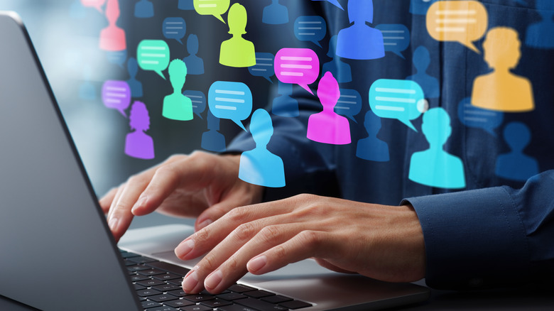 Person typing on laptop with messaging icons displayed above their hands