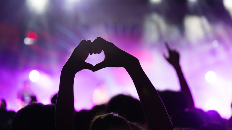 Hands in a crowd making the shape of a heart at a concert