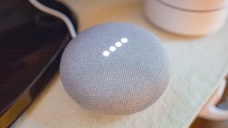 Google Home mini on a tabletop next to a Google WiFi node.