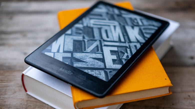 An Amazon Kindle on top of a stack of books