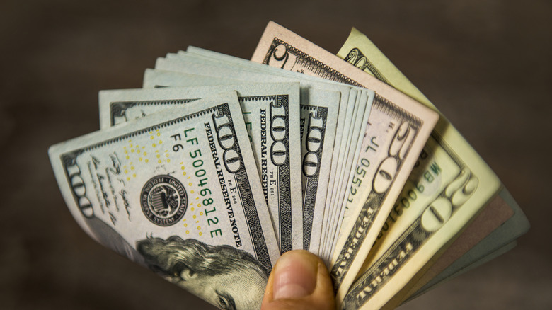 Person holding a wad of dollar bills
