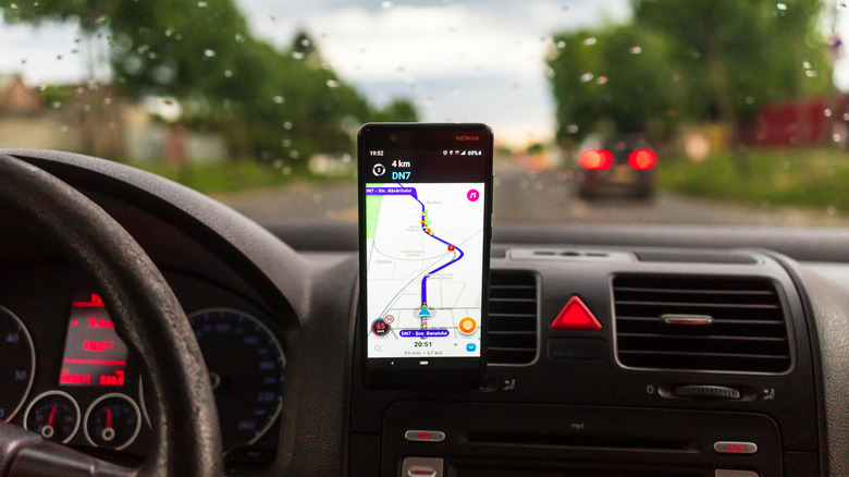 Phone in holder in car with Waze on the screen showing route
