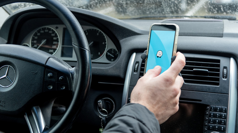 Phone held in hand with Waze logo on screen with blue background