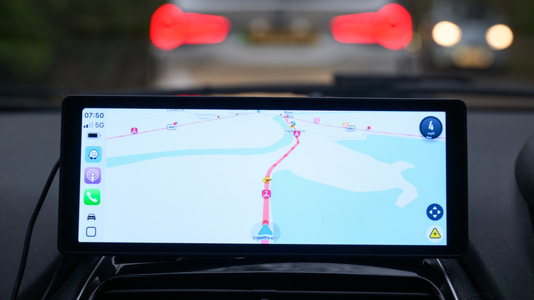 Waze app on console screen in car showing route with taillights showing in the window above