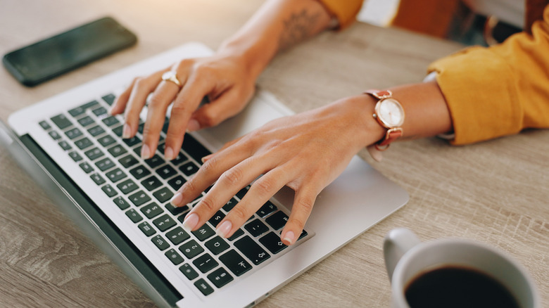 Typing, laptop and freelancer with hands of woman in home office for copywriter, research and blog article.