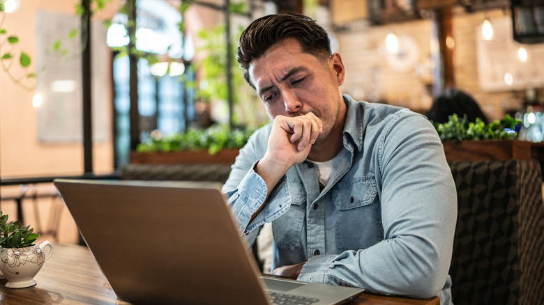 Worried businessman using laptop in a coffee shop