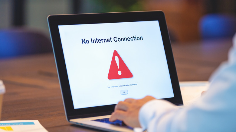 person working on a laptop that reads No Internet Connection