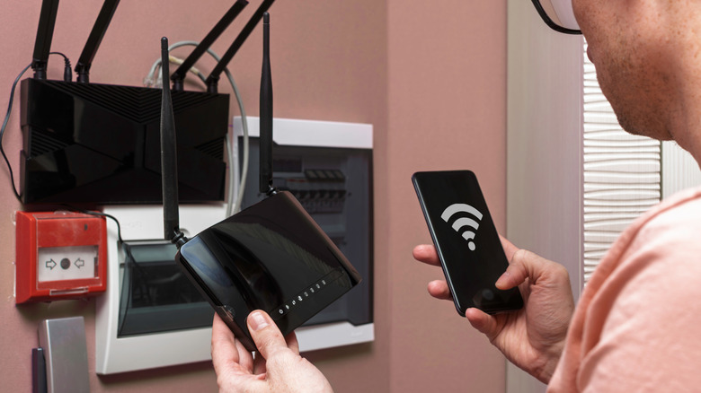 person configuring a black wi-fi router