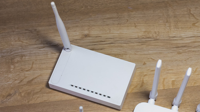 an old white router with a single antenna placed on a wooden surface