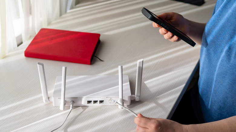 person configuring a new wi-fi router place on a white table