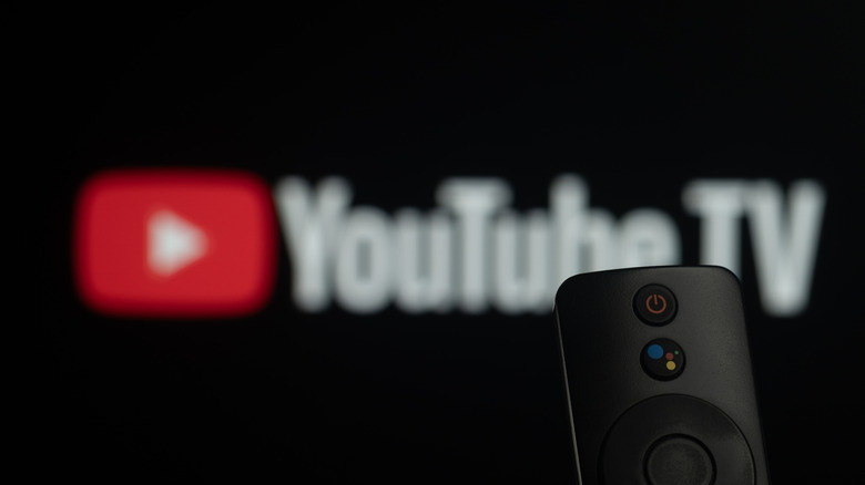 Close-up of a smart TV remote control against a blurred Youtube TV logo
