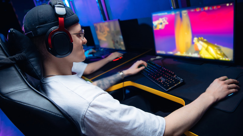 Person wearing headphones playing a first-person shooter game on a PC setup