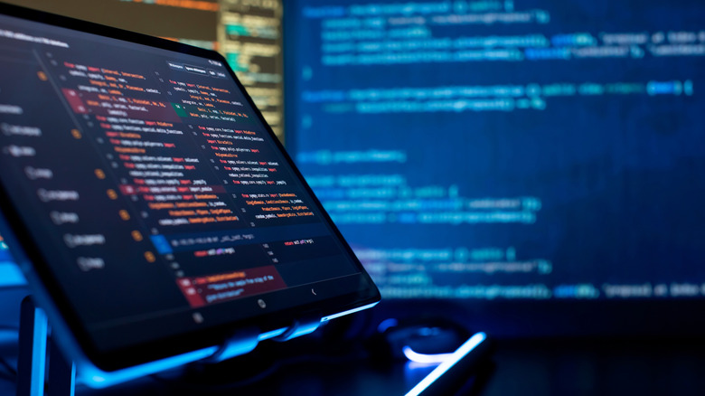 Screen displaying lines of code with a blurred programming screen in the background