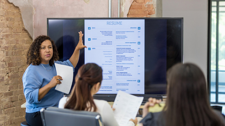 A woman showing a resume template on a large screen to a group sitting in front of it