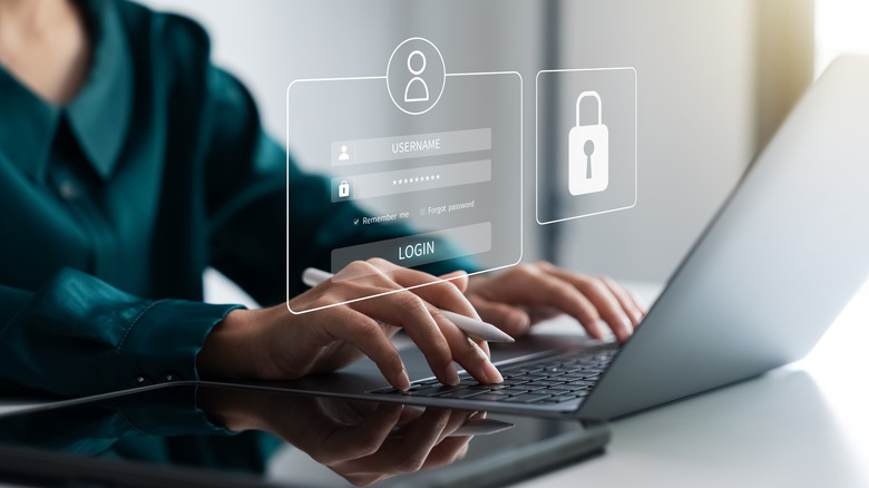 A person entering a password into a laptop with a mobile device nearby
