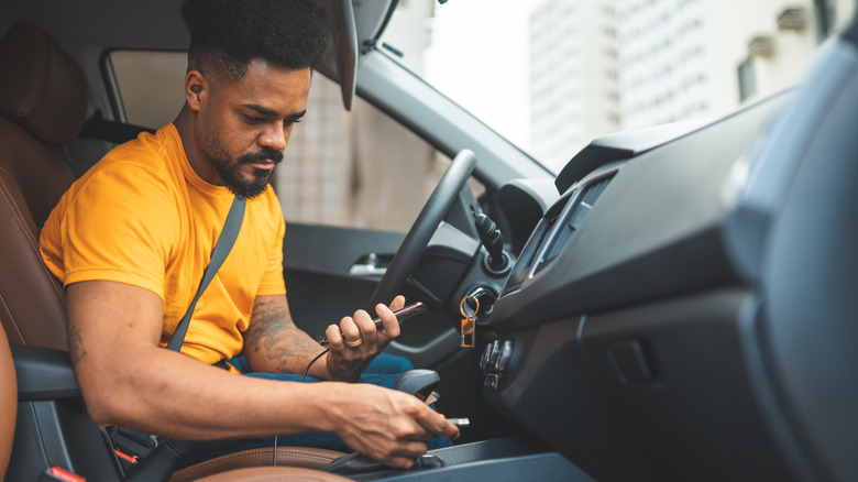 A man plugging a cable into a USB port of a car.