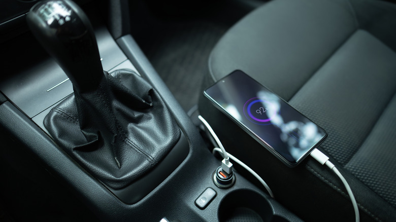 A phone charging in a car, plugged into a USB port.