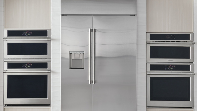 A closed Monogram fridge in a kitchen area surrounded by Monogram ovens