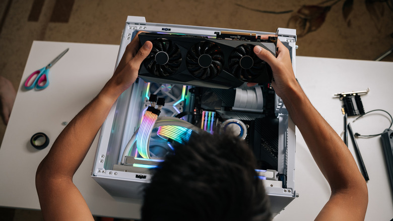 Person installing a graphics card inside a desktop PC.