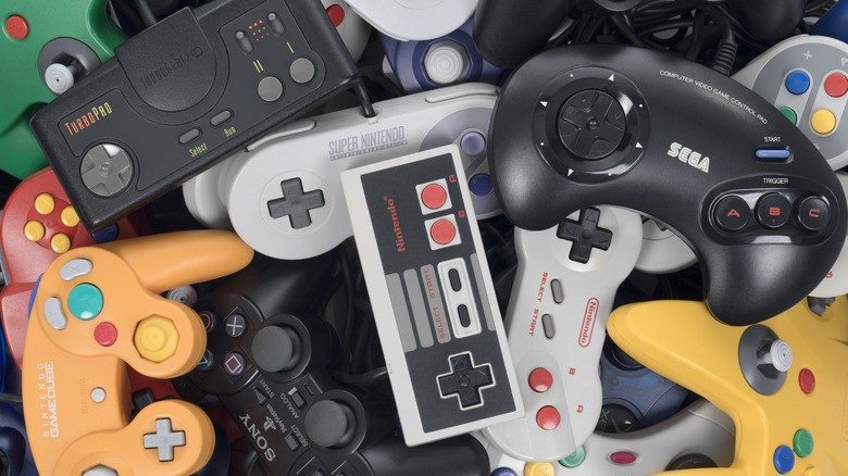 Pile of retro video game controllers including Nintendo, Sega, and GameCube gamepads.