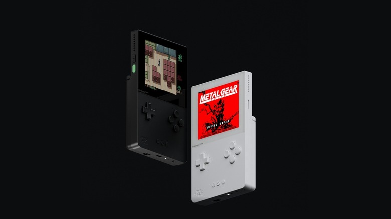 Two Analogue Pocket handhelds, black and white, on a black background. The handhelds resemble the original Game Boy.