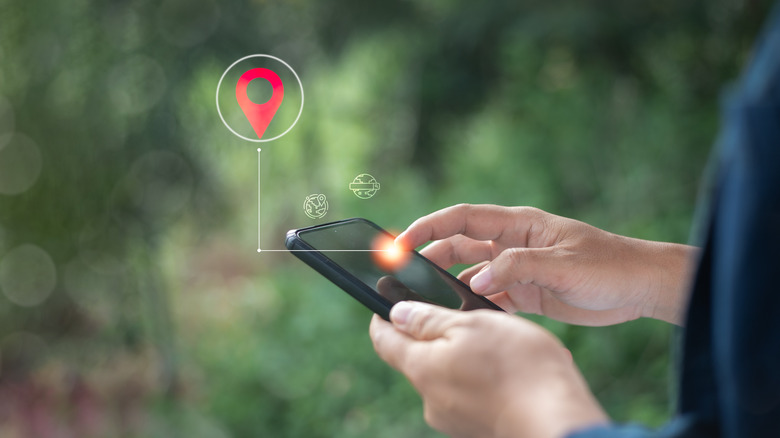 person holding a smartphone with a graphical location pin icon above it