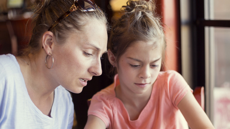 Mother checking her daughters smartphone activity with her
