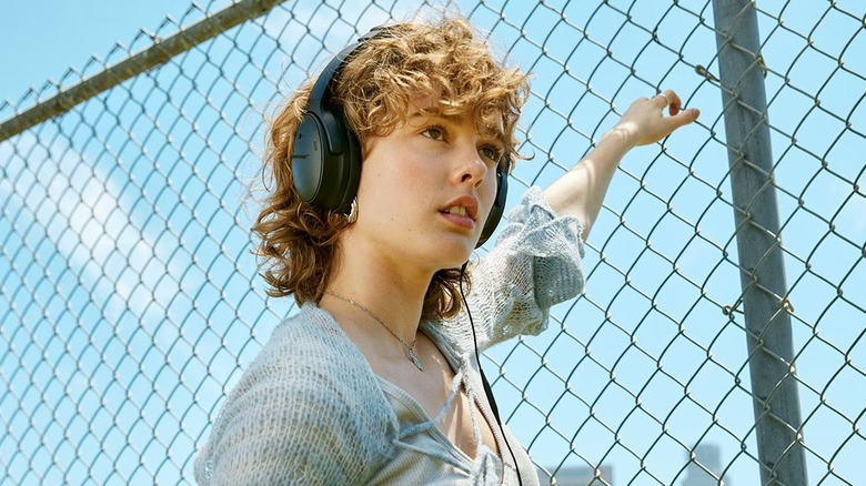 A person wearing Bose QuietComfort wireless headphones while outdoors.
