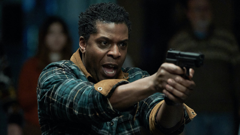 Milton Barnes as Miles holding a handgun in the series Station Eleven