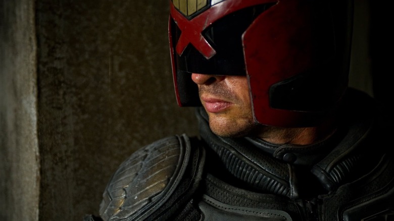 Karl Urban as Judge Dredd stood against a wall in Dredd (2012)