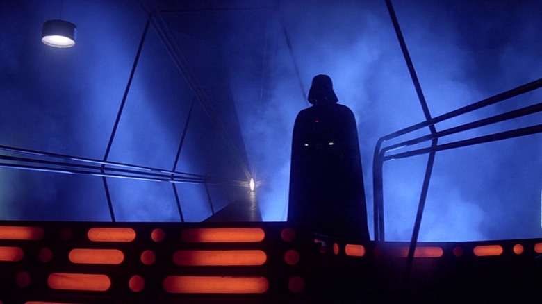 Darth Vader standing at the top of stairs in a dark room.