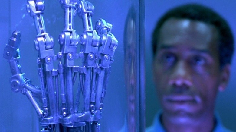 Joe Morton as Miles Dyson looks at the naked hand of a T-800 cyborg as it is encased in glass