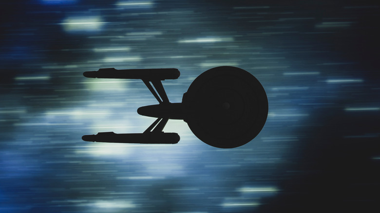 The Stark Trek Enterprise silhouetted as it speeds through space