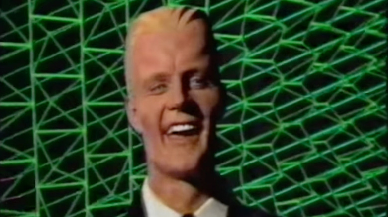 The character Max Headroom laughing against a colorful backdrop